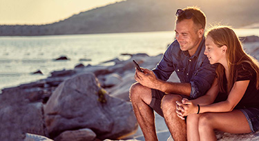 Father and daughter enjoying time together looking at a smartphone by the sea